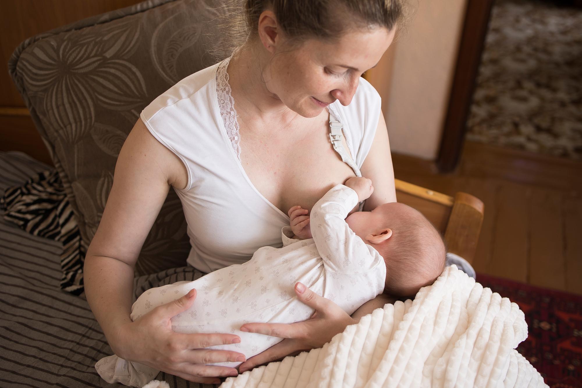 Mother breastfeeding newborn baby with proper latch and positioning