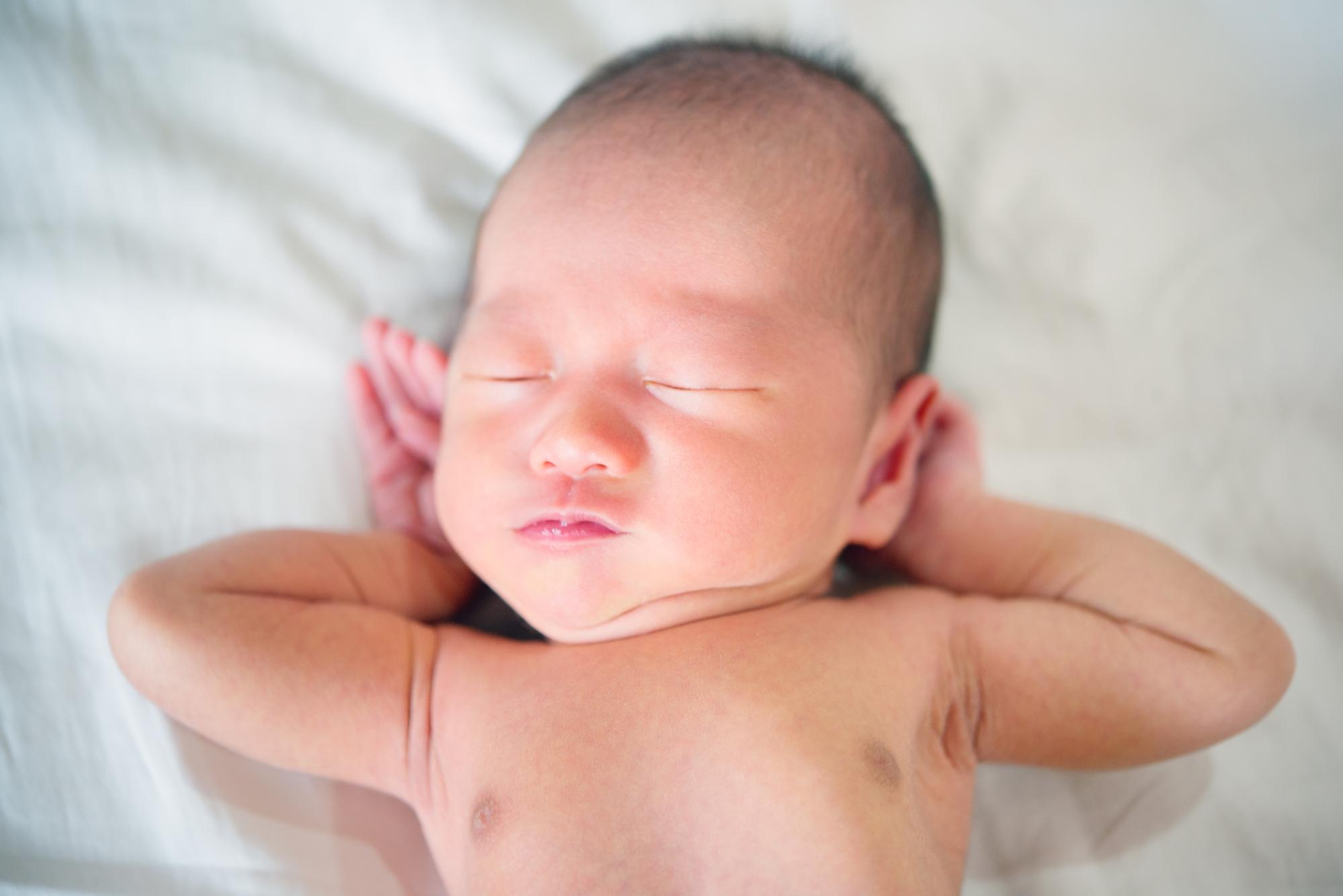 Peaceful newborn baby sleeping with visible gentle chest movements showing normal breathing pattern