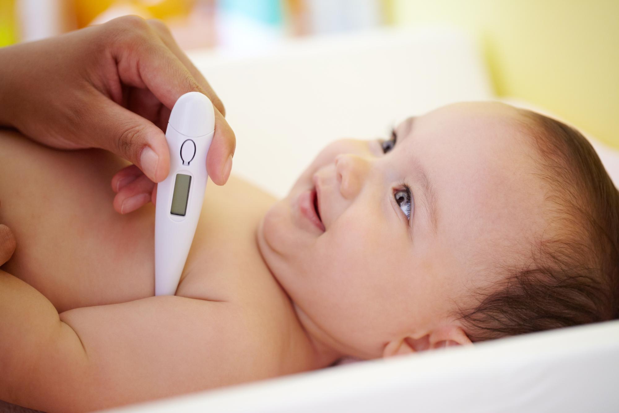Newborn baby being examined by pediatrician with thermometer for fever assessment