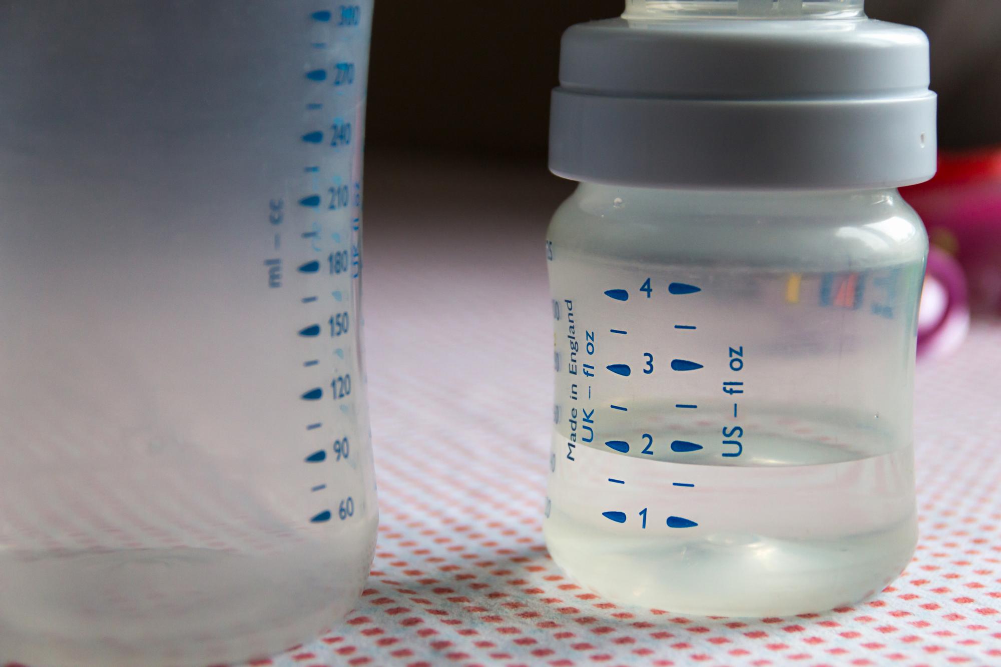 Newborn baby bottle with measured formula amounts showing proper feeding quantities