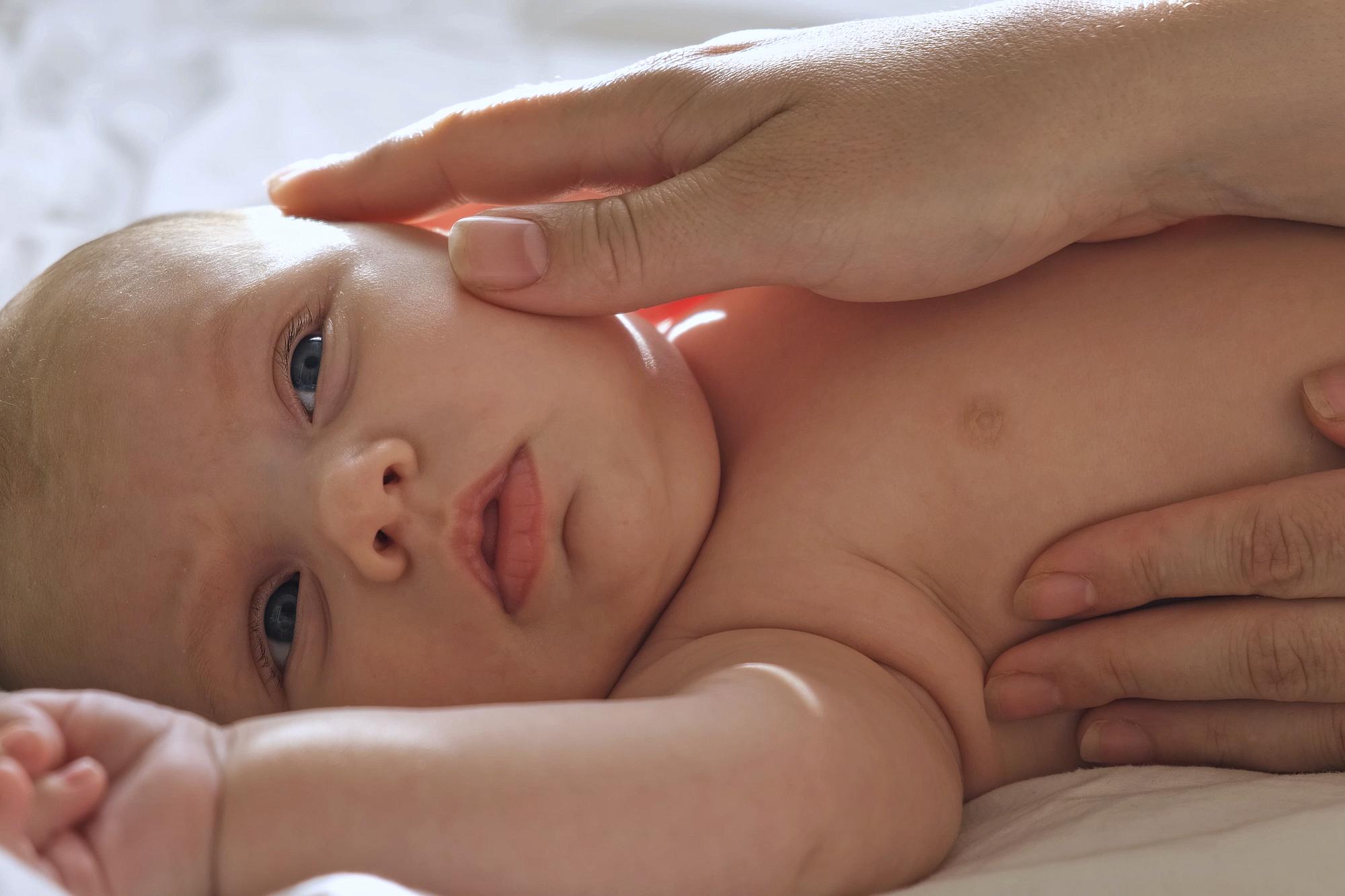 Close-up of newborn baby with mild jaundice showing yellowing of skin being examined by pediatrician