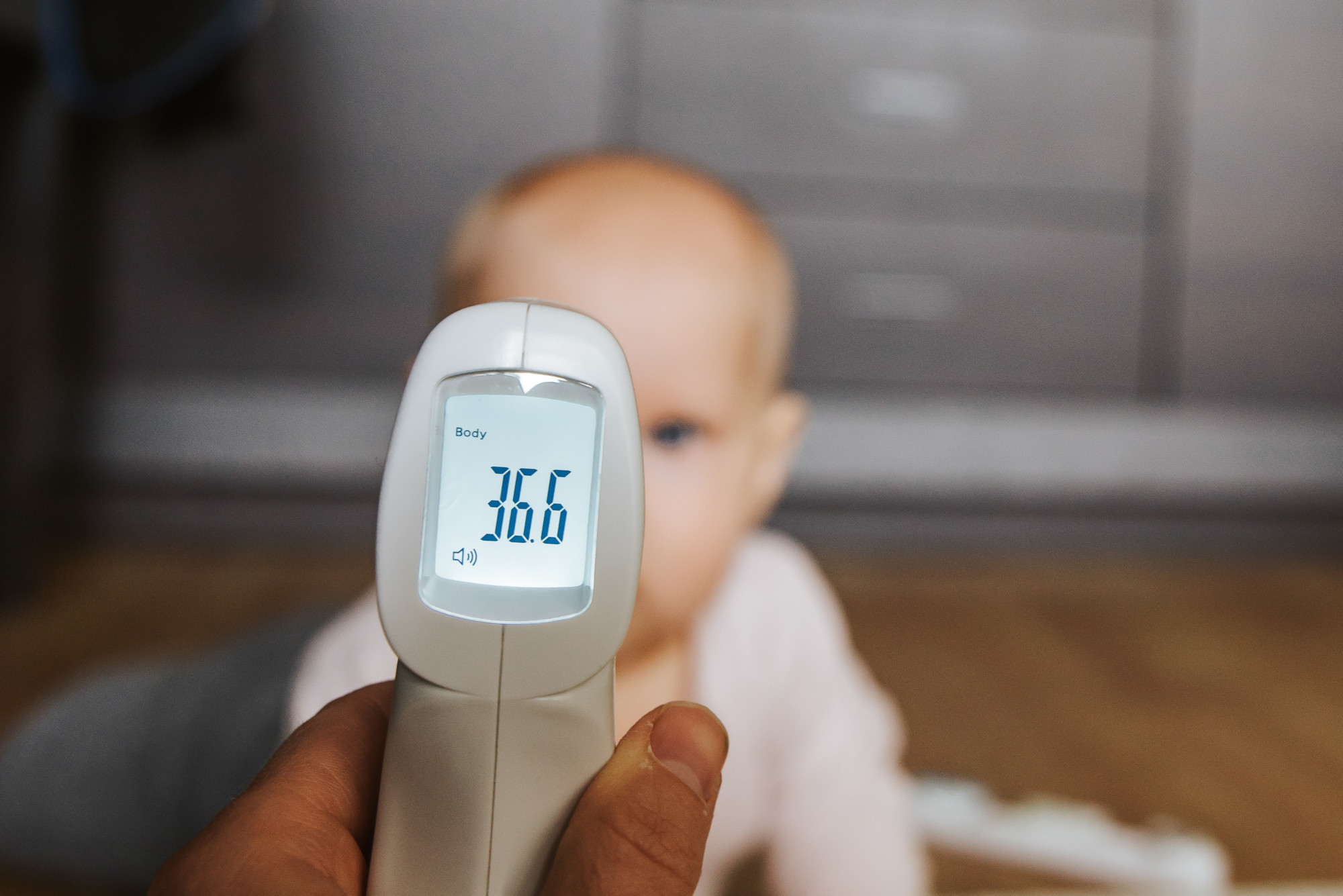Parent checking newborn baby temperature with digital thermometer in nursery