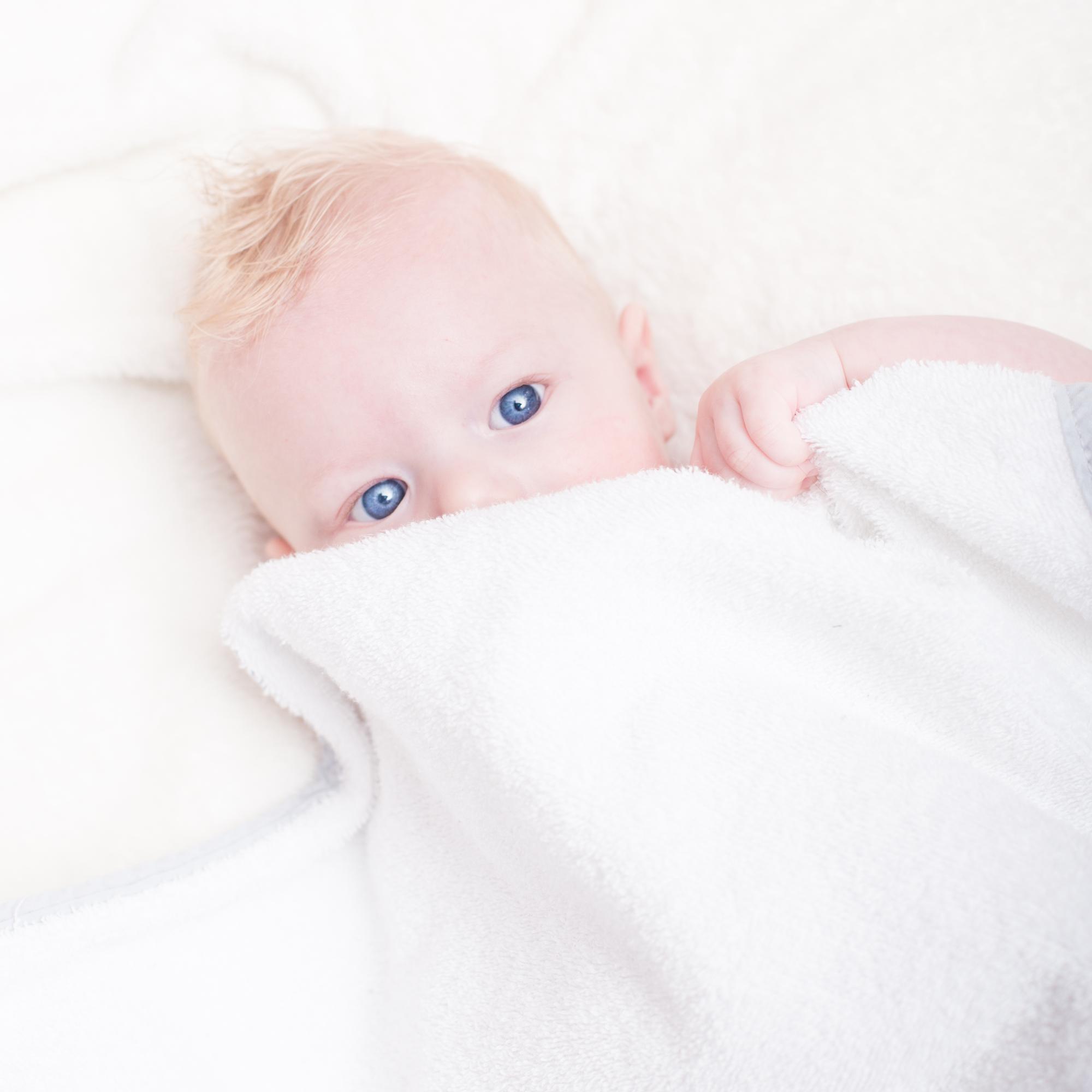 Close-up of peaceful newborn baby with clear skin lying on white blanket