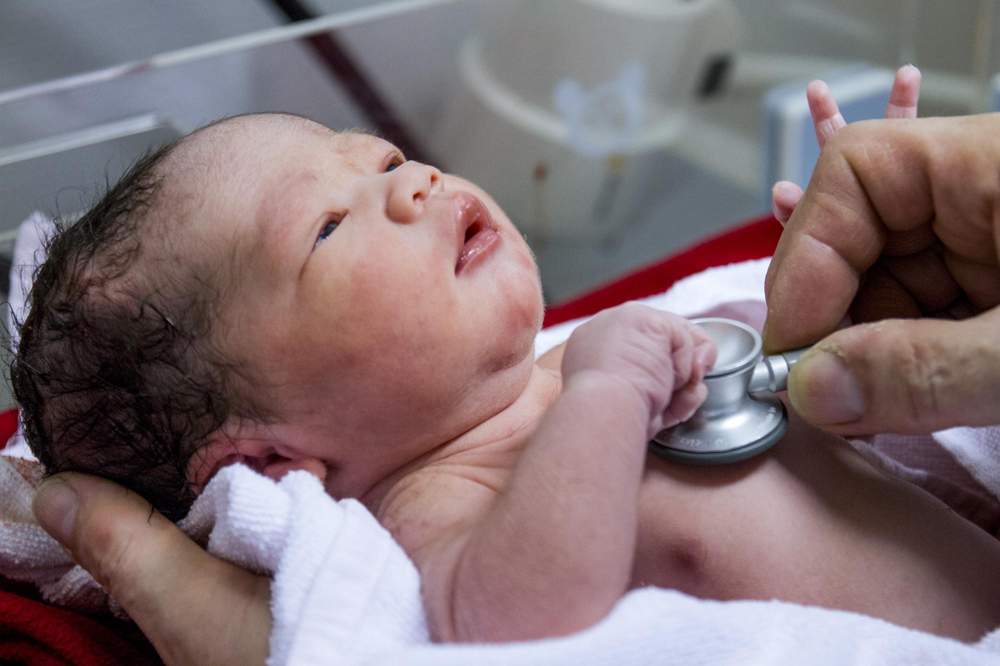 Cropped hands of doctor checking baby boy at hospital