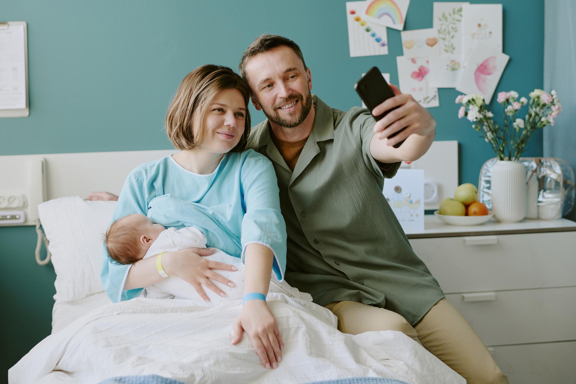 Parent holding baby while looking at phone to decide between hospital or home doctor visit in Tbilisi