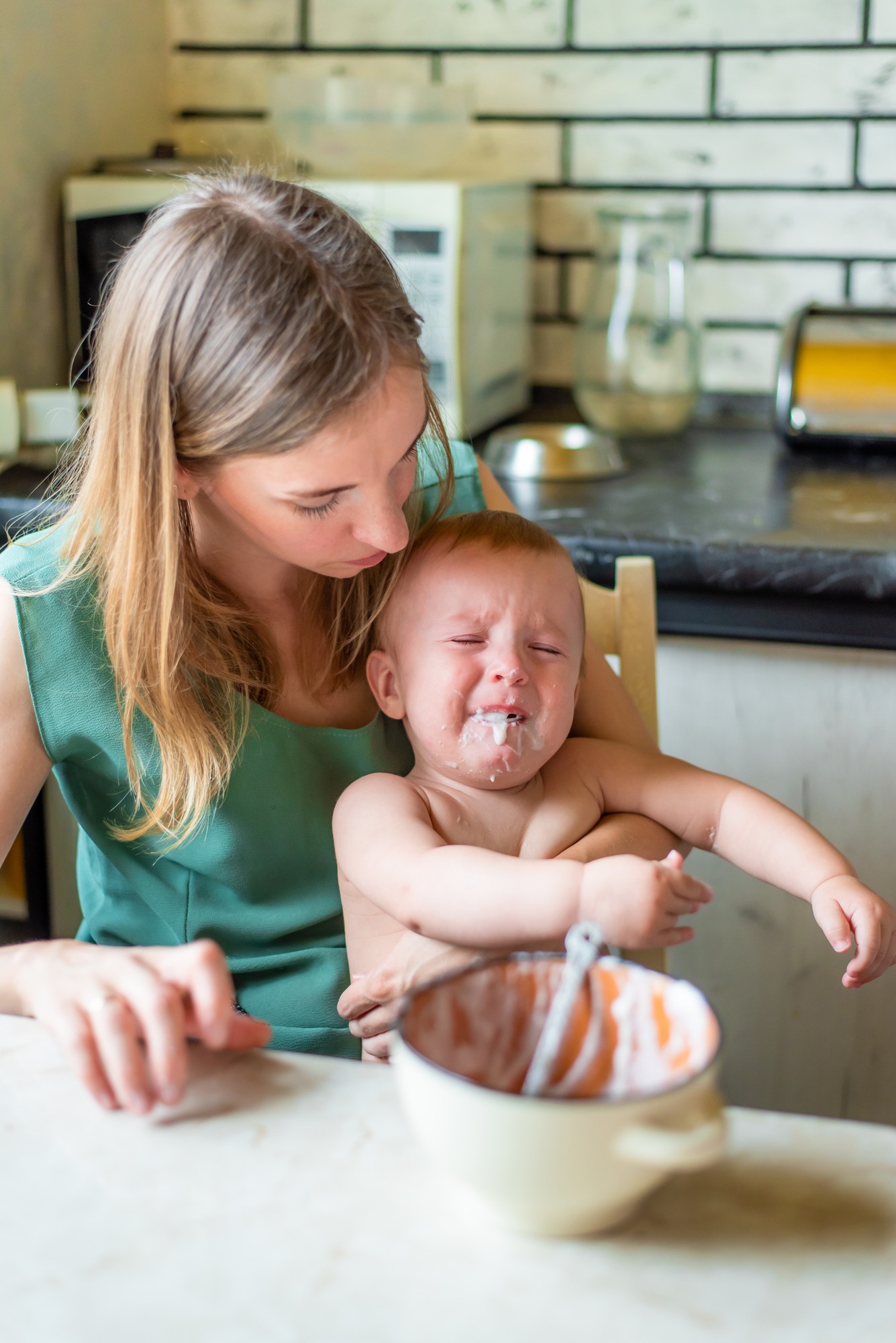 Newborn baby crying while being held by caring parent during feeding time