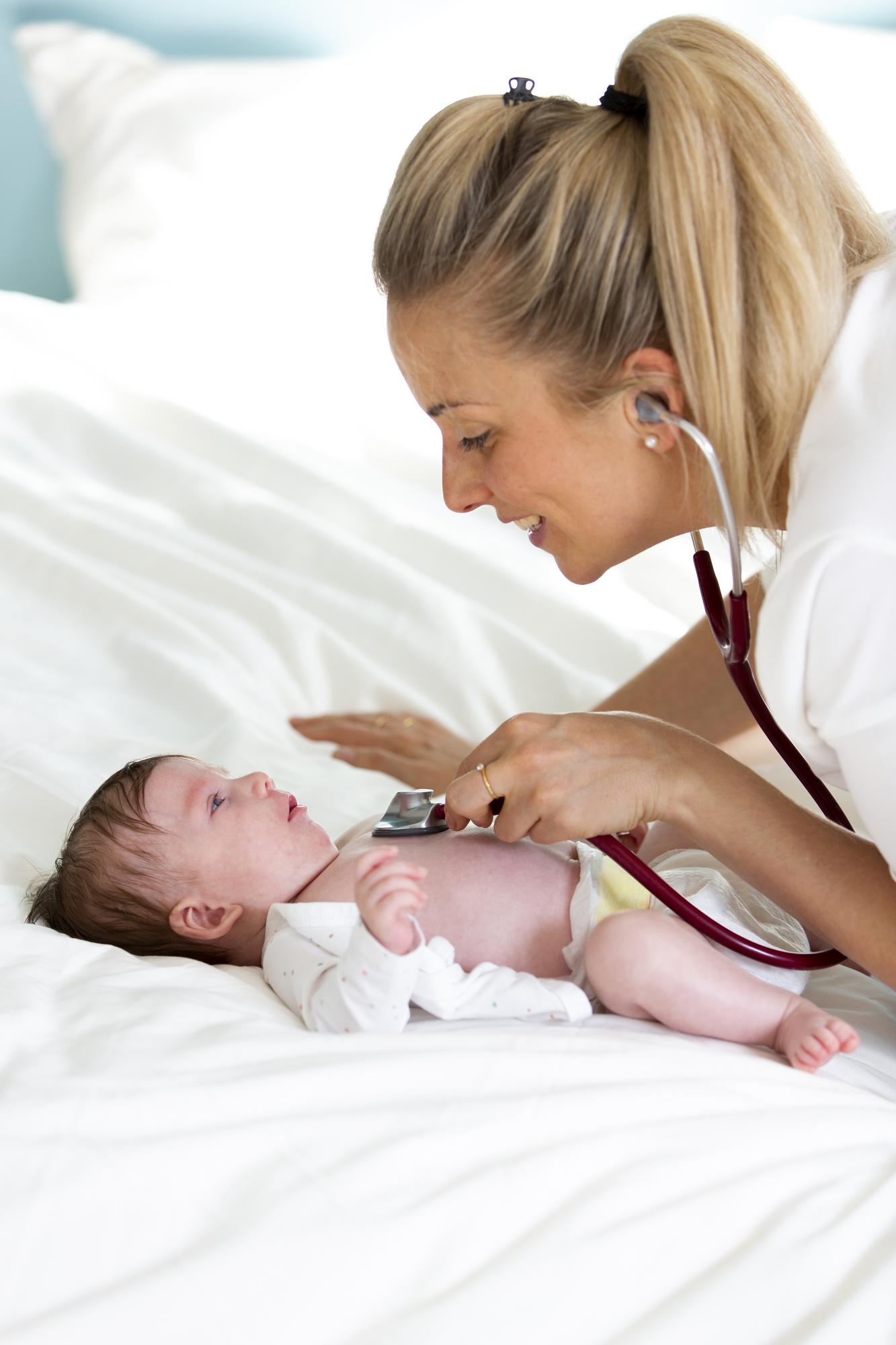 doctor examining newborn baby at home visit